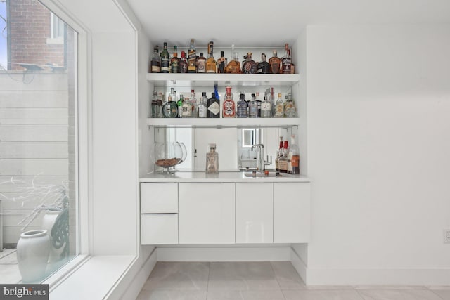 bar with a dry bar, light tile patterned flooring, baseboards, and a sink