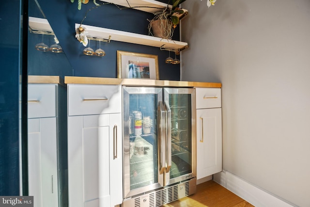 interior space featuring beverage cooler, baseboards, and wood finished floors