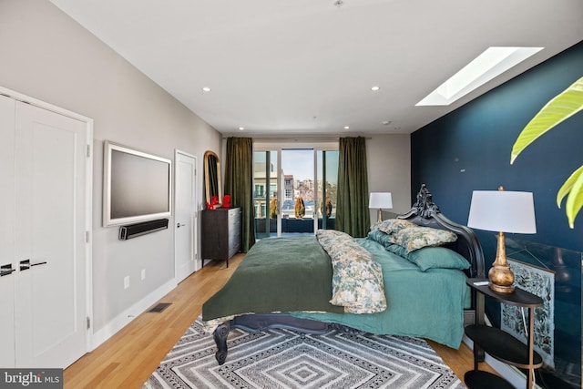 bedroom with recessed lighting, a skylight, wood finished floors, visible vents, and baseboards