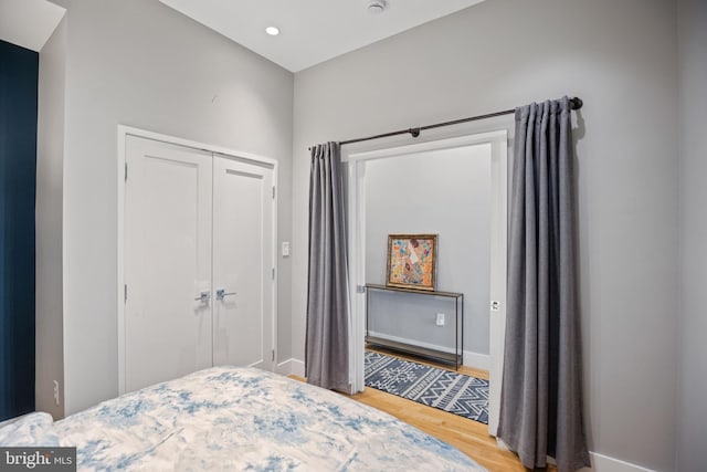 bedroom featuring a closet, recessed lighting, wood finished floors, and baseboards