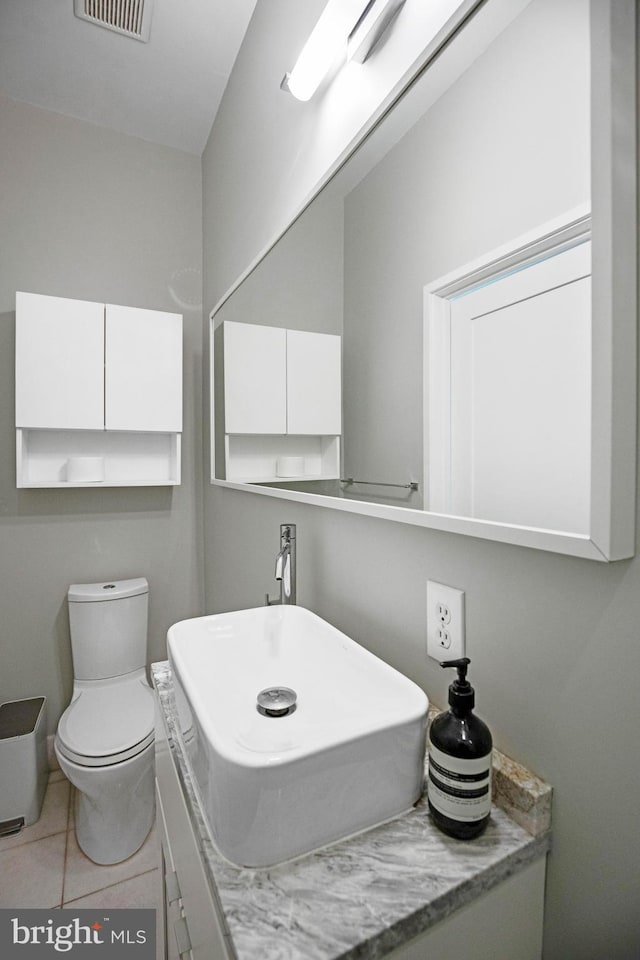 half bathroom featuring toilet, tile patterned flooring, visible vents, and a sink