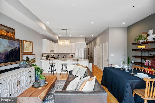 living room featuring a notable chandelier, light wood-type flooring, and recessed lighting