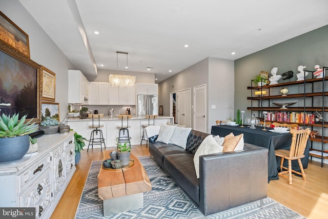 living room featuring recessed lighting, light wood-style flooring, and an inviting chandelier