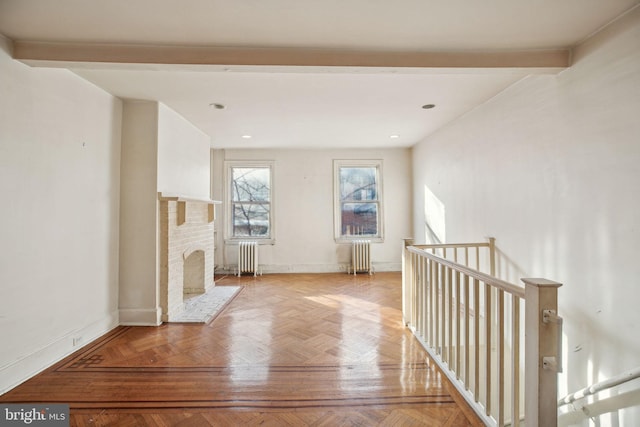 unfurnished living room with baseboards, a fireplace, beam ceiling, and radiator