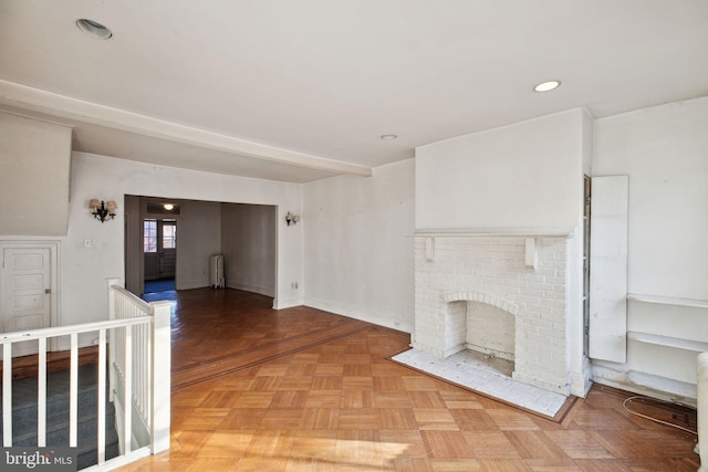 unfurnished living room featuring radiator, a brick fireplace, and recessed lighting