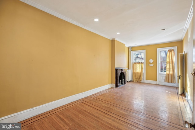 unfurnished living room featuring ornamental molding, wood-type flooring, a fireplace, and baseboards