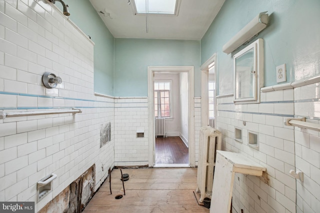 washroom with hardwood / wood-style floors, radiator heating unit, and tile walls