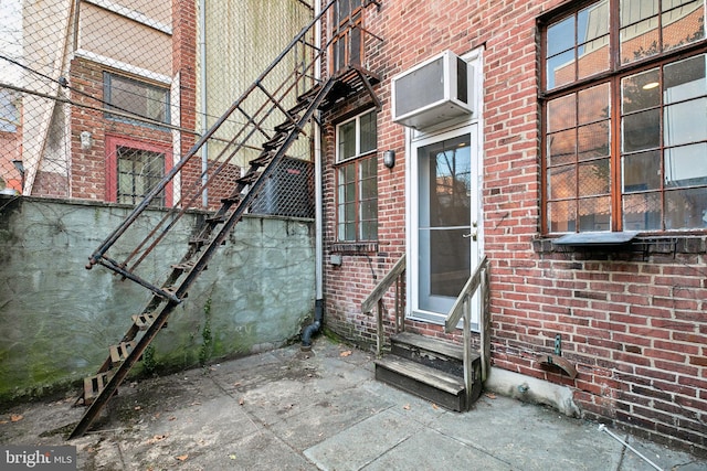 entrance to property with an AC wall unit and brick siding