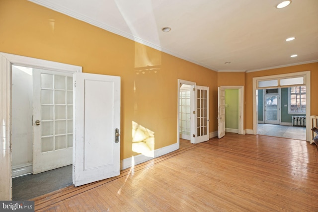 unfurnished room featuring french doors, crown molding, radiator heating unit, and wood finished floors