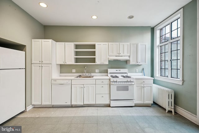 kitchen with white appliances, radiator heating unit, light countertops, under cabinet range hood, and recessed lighting