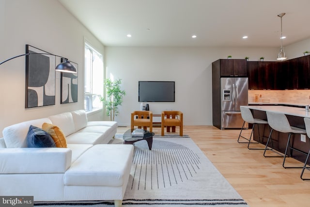 living room with light wood-style floors, recessed lighting, and baseboards