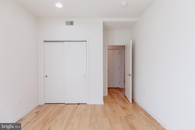 unfurnished bedroom featuring baseboards, a closet, visible vents, and light wood-style floors