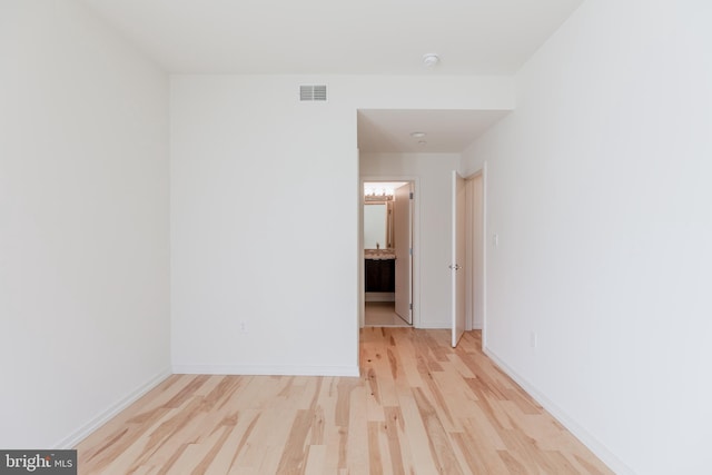 empty room with light wood finished floors, baseboards, and visible vents