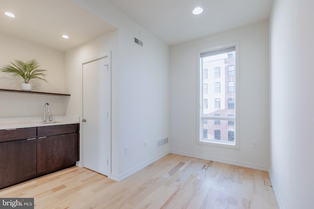 interior space with light wood-style floors, light countertops, visible vents, and dark brown cabinets