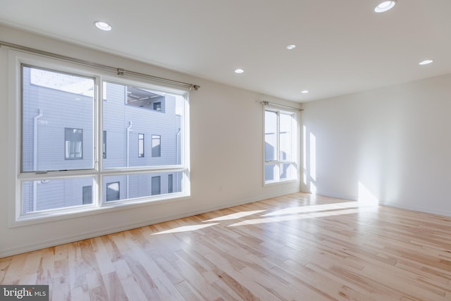 spare room with baseboards, light wood finished floors, and recessed lighting