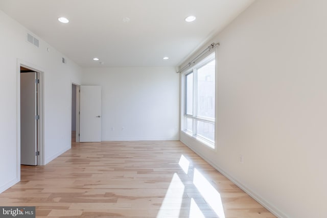 unfurnished room with light wood finished floors, baseboards, visible vents, and recessed lighting