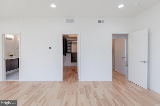 unfurnished bedroom featuring light wood-type flooring, a walk in closet, visible vents, and recessed lighting