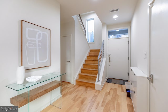 interior space with light wood finished floors, recessed lighting, visible vents, stairway, and baseboards