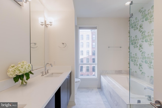 full bath with double vanity, tiled tub, a sink, and toilet