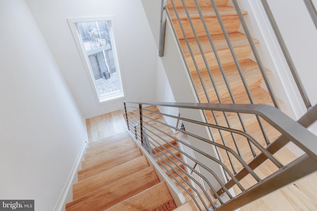 staircase featuring baseboards and wood finished floors