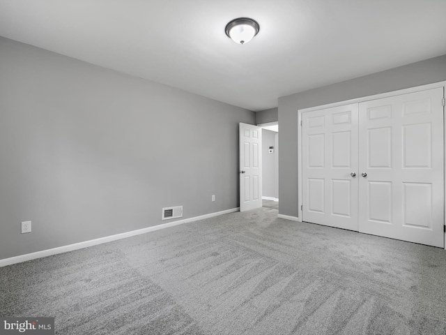 unfurnished bedroom featuring carpet floors, baseboards, visible vents, and a closet