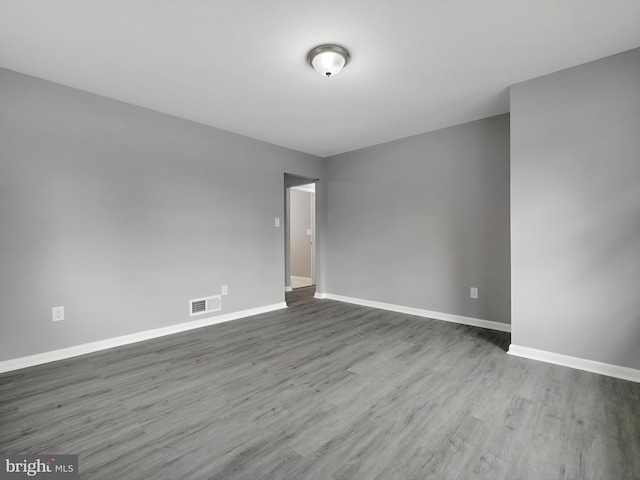 empty room featuring baseboards, visible vents, and wood finished floors