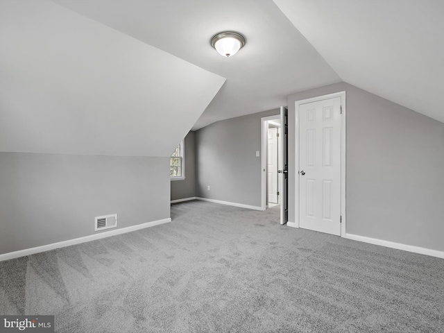 additional living space featuring visible vents, vaulted ceiling, light carpet, and baseboards