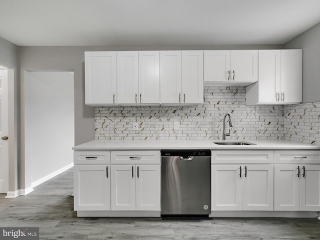 kitchen with light countertops, dishwasher, a sink, and white cabinetry