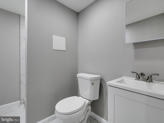 bathroom featuring toilet, marble finish floor, baseboards, and vanity