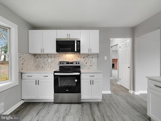 kitchen featuring stainless steel appliances, light countertops, and white cabinets