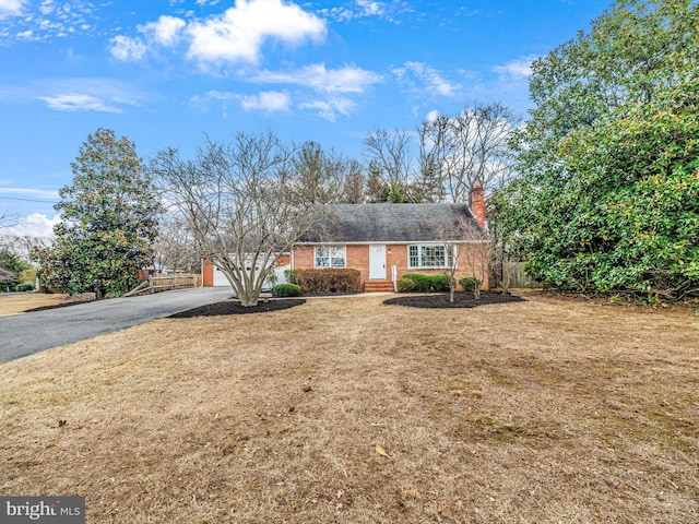 ranch-style house featuring a garage, driveway, brick siding, and a front yard