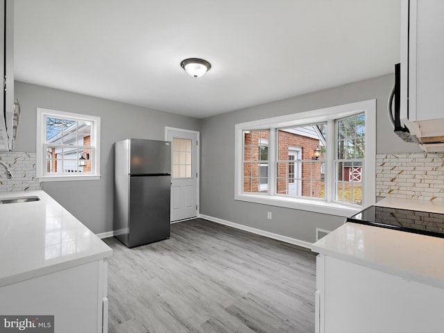 kitchen featuring white cabinets, light countertops, a sink, and freestanding refrigerator