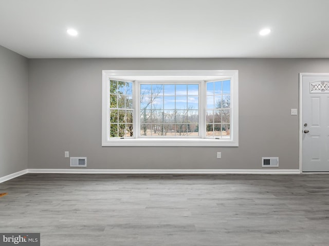 foyer entrance with visible vents, baseboards, and wood finished floors