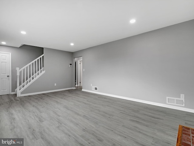 unfurnished living room featuring recessed lighting, wood finished floors, visible vents, baseboards, and stairway