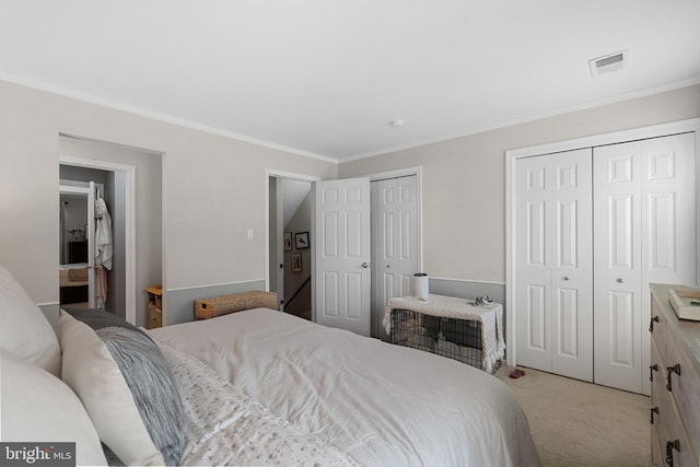 bedroom with multiple closets, light carpet, crown molding, and visible vents