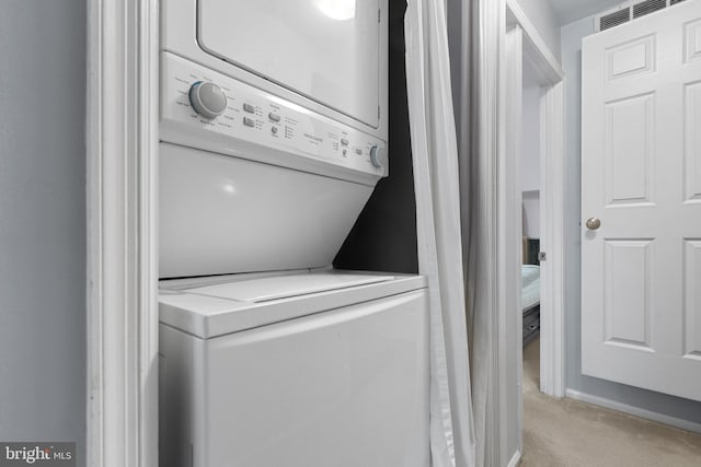 laundry area with light carpet, visible vents, and stacked washer / drying machine