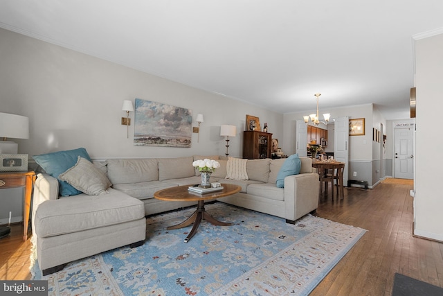 living room featuring baseboards, ornamental molding, hardwood / wood-style flooring, and an inviting chandelier