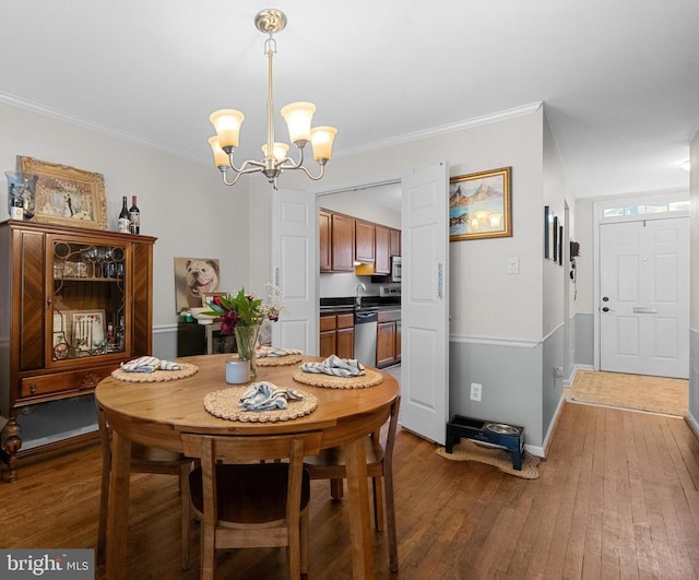 dining area with a chandelier, light wood finished floors, ornamental molding, and baseboards