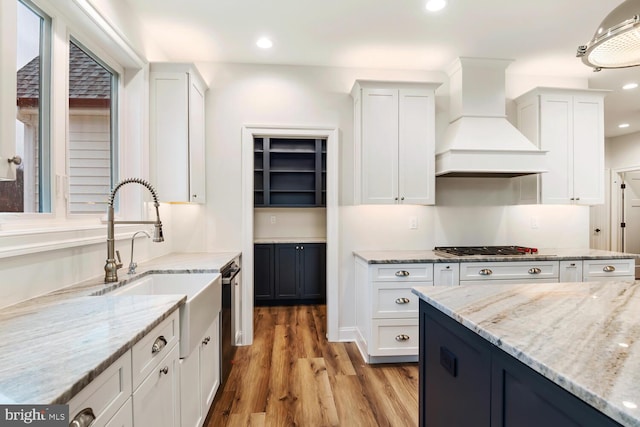 kitchen featuring light stone counters, white cabinets, and custom exhaust hood