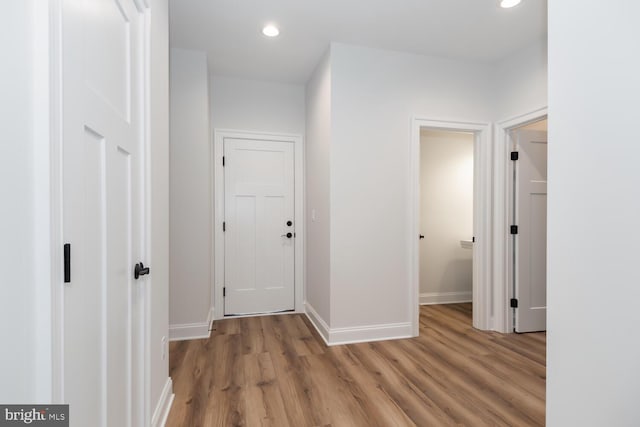 hall featuring light wood finished floors, recessed lighting, and baseboards