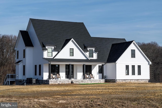 view of front of home featuring a porch, a front lawn, board and batten siding, and central air condition unit