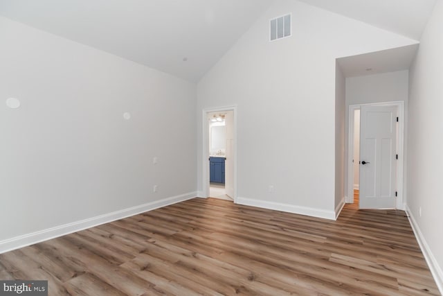 unfurnished bedroom with high vaulted ceiling, visible vents, baseboards, and wood finished floors