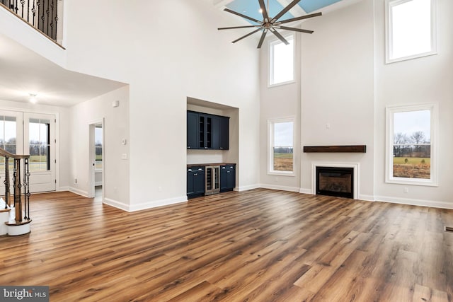 unfurnished living room with beverage cooler, a fireplace, baseboards, and dark wood-type flooring