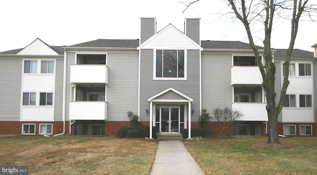 view of front of house featuring a balcony, a chimney, and a front yard