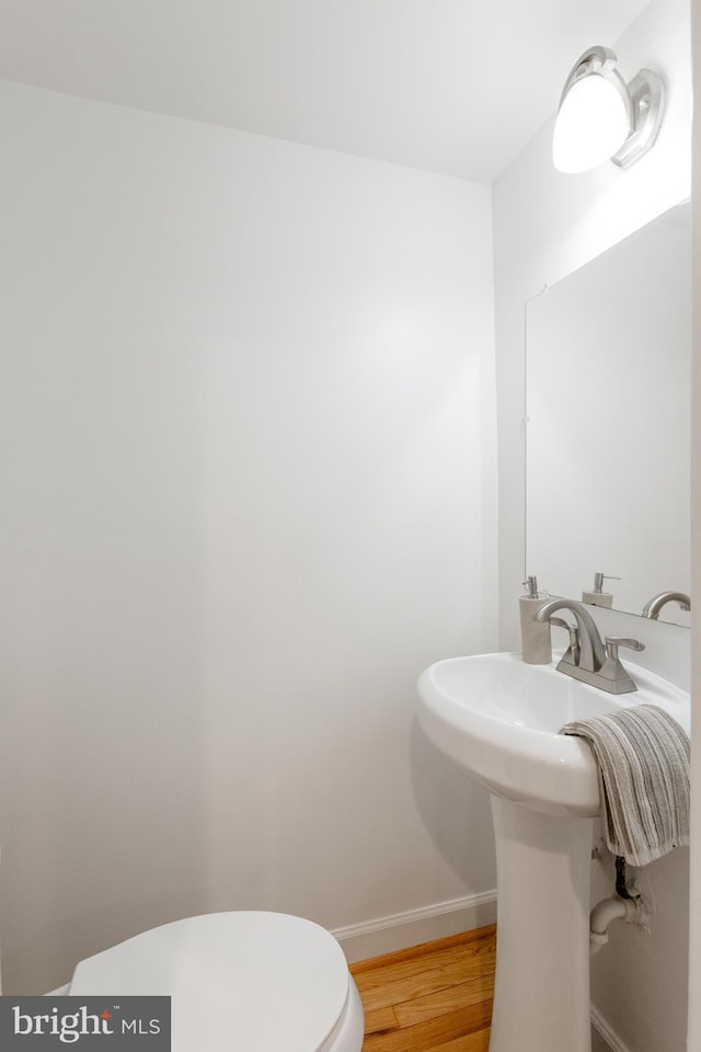 half bath featuring toilet, baseboards, and wood finished floors