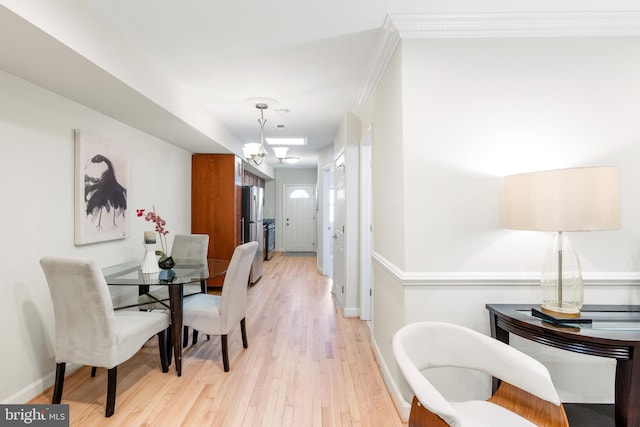 dining area featuring crown molding, light wood-type flooring, an inviting chandelier, and baseboards