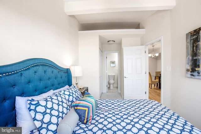 bedroom featuring connected bathroom, beam ceiling, and a notable chandelier