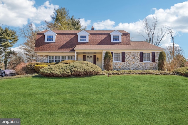 view of front of property with stone siding, roof with shingles, a chimney, and a front lawn