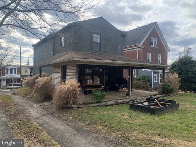 back of house with a yard and a garden