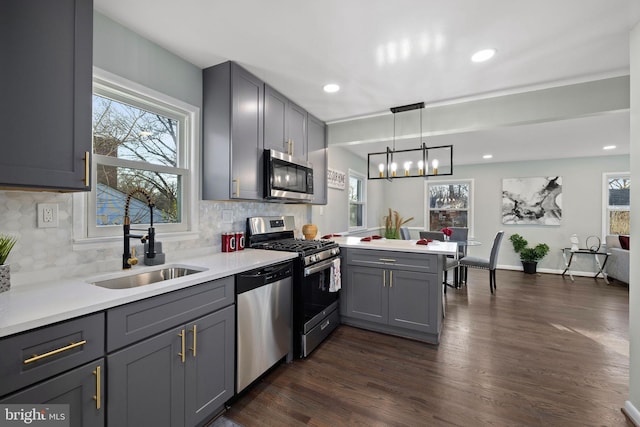 kitchen featuring a peninsula, appliances with stainless steel finishes, gray cabinets, and a sink